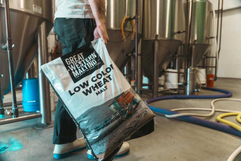 Bag of Low Color Wheat Malt being carried by brewer through brewery